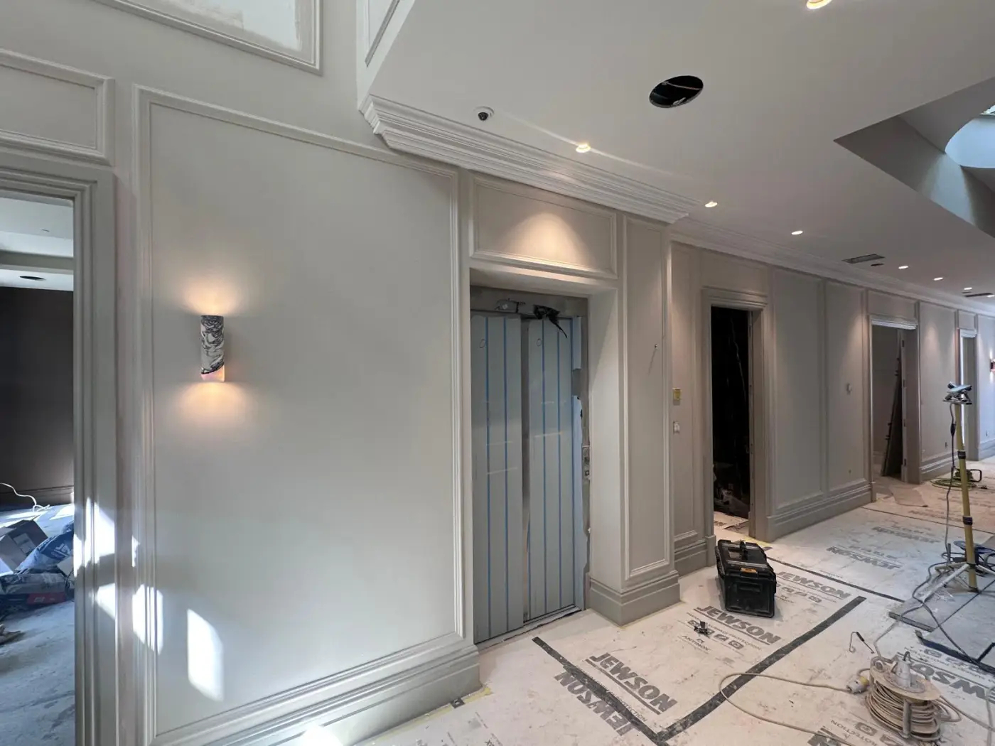Panelled corridor with wall lights and passenger lift, upper floors