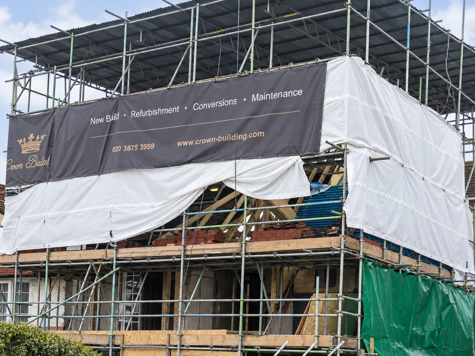 Period house in Golders Green under full scaffold and a temporary roof during a mansard loft conversion, Crown Building banner